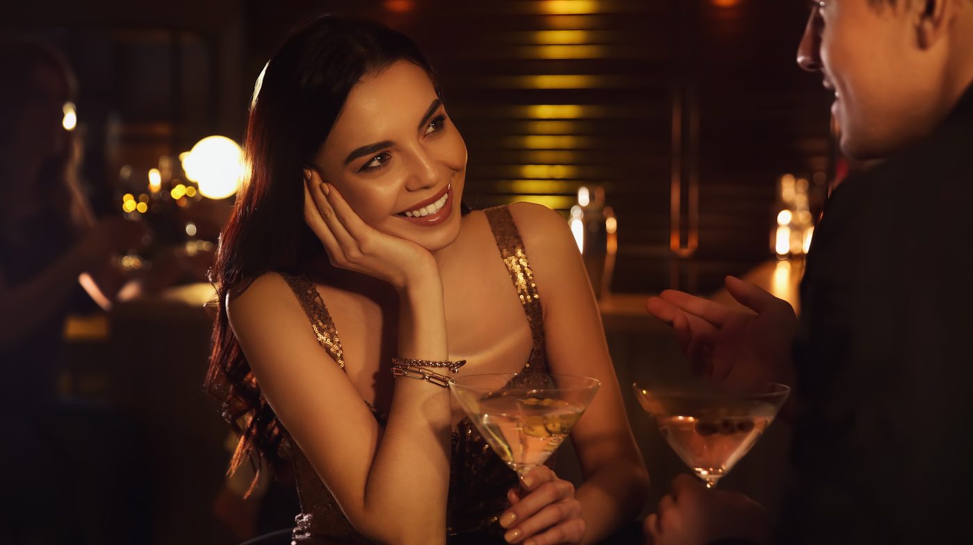 A first drink in a quiet bar, smiling conversation over two martini glasses